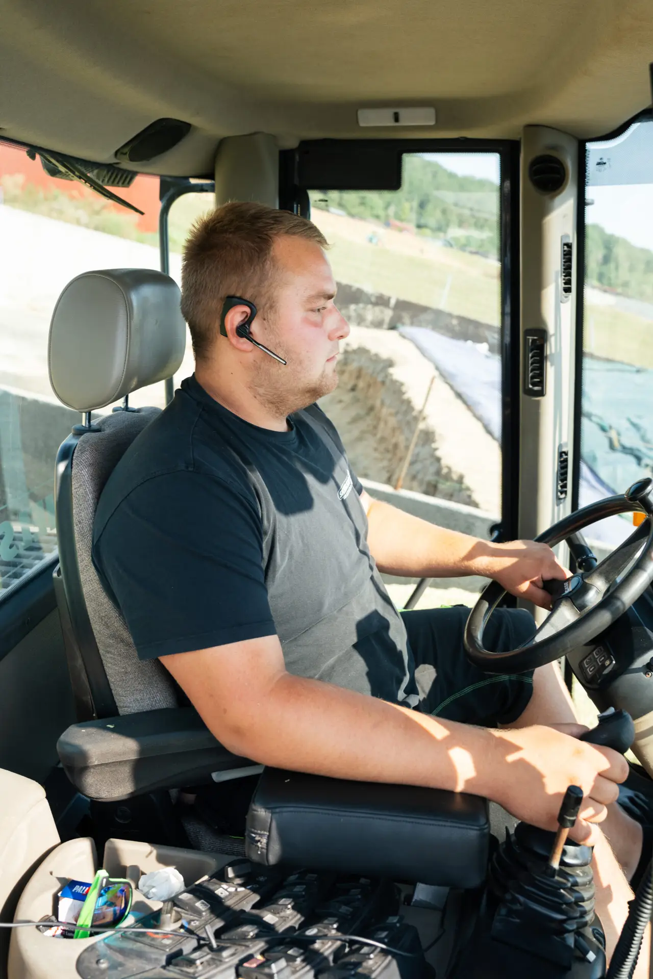 Junger Mann steuert einen Radlader bei landwirtschaftlichen Arbeiten in einem Silo. Professionelle Steuerung von Maschinen im Bereich Landwirtschaft und Erdarbeiten.