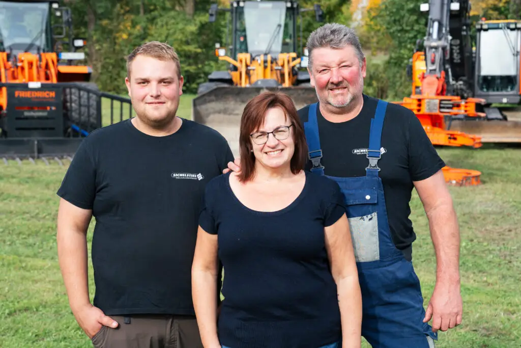 Familienunternehmen im Bereich Forst- und Baggerarbeiten: Vater, Mutter und Sohn vor Arbeitsmaschinen. Das Team führt professionelle Erd- und Forstarbeiten in der Region Neustadt an der Aisch durch.